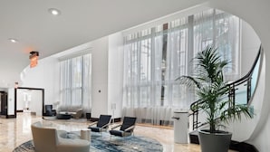 A spacious lobby with a marble floor, large windows, and modern seating.