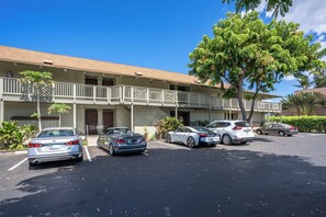 A multi-story building with a parking lot. There are several cars parked in the lot. - Kihei Bay Surf #226 Convenient, Shared Hot Tub, Near Beach, Great Rates! (Kihei)