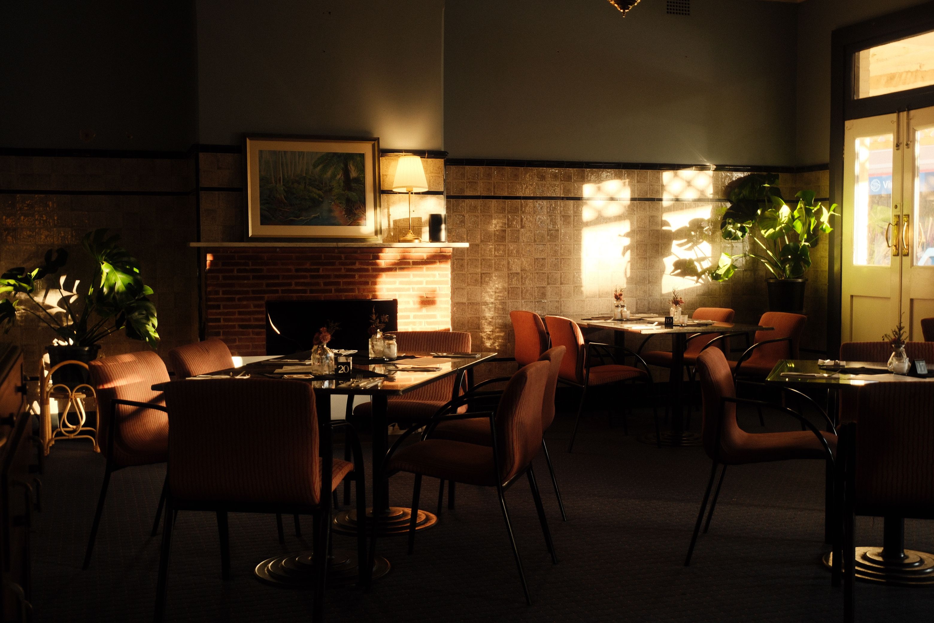 Un restaurante con poca luz, paredes de ladrillo, chimenea y una mesa dispuesta para comer.