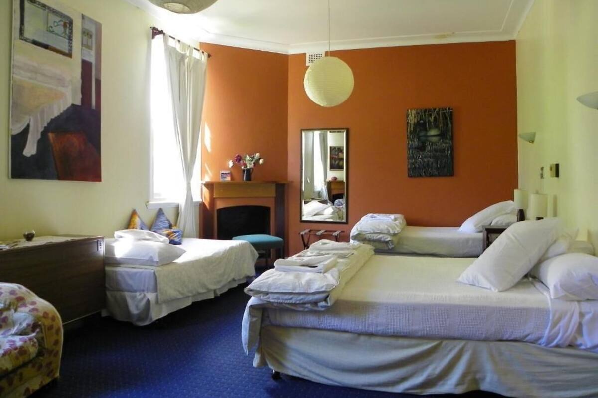 Habitación de hotel con dos camas individuales, un escritorio, una silla, un espejo y una chimenea.