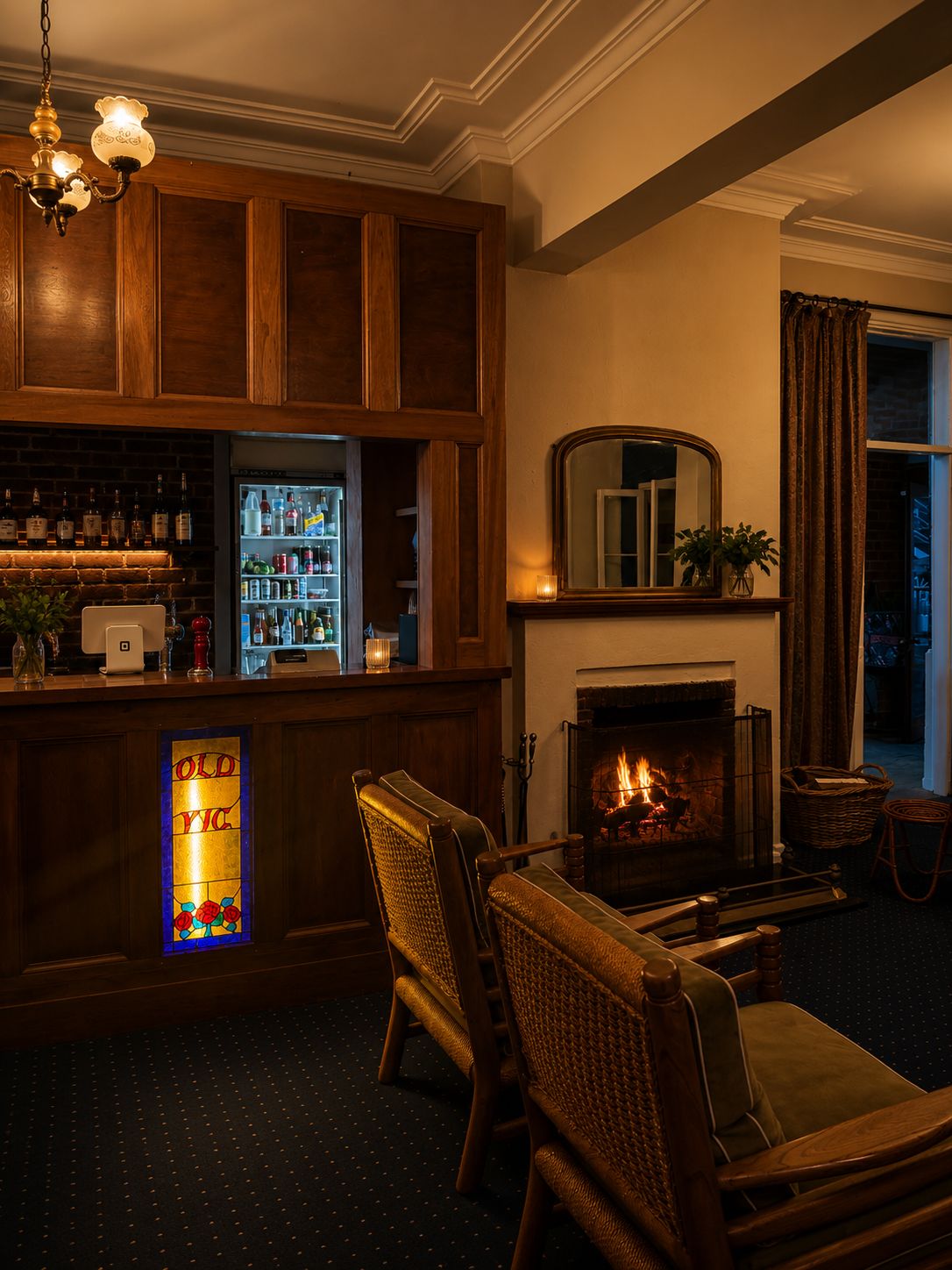 A bar area with a fireplace, wooden furniture, and a bar stocked with bottles.