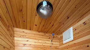 Bagno con rivestimento in legno, dotato di WC, doccia e lavandino.
