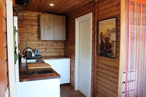 Una cocina pequeña con paredes de madera, una puerta blanca y un cartel en la pared.