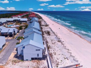 Ein Küstenhotel mit mehreren Gebäuden, einem Strand und Meerblick.