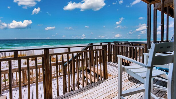 Une terrasse en bois offrant une vue sur la plage et l’océan.
