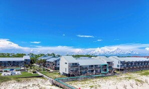 Ein Küstenhotel mit mehreren Gebäuden, einem Pool und Blick auf den Strand.
