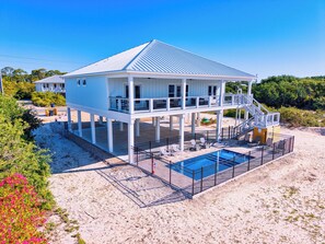 A beachfront house with a pool, a balcony, and a covered area. - Shrimper and Grits, New Construction, Private Pool, Short Walk to Beach, Beach Gear Credit (St. George Island)