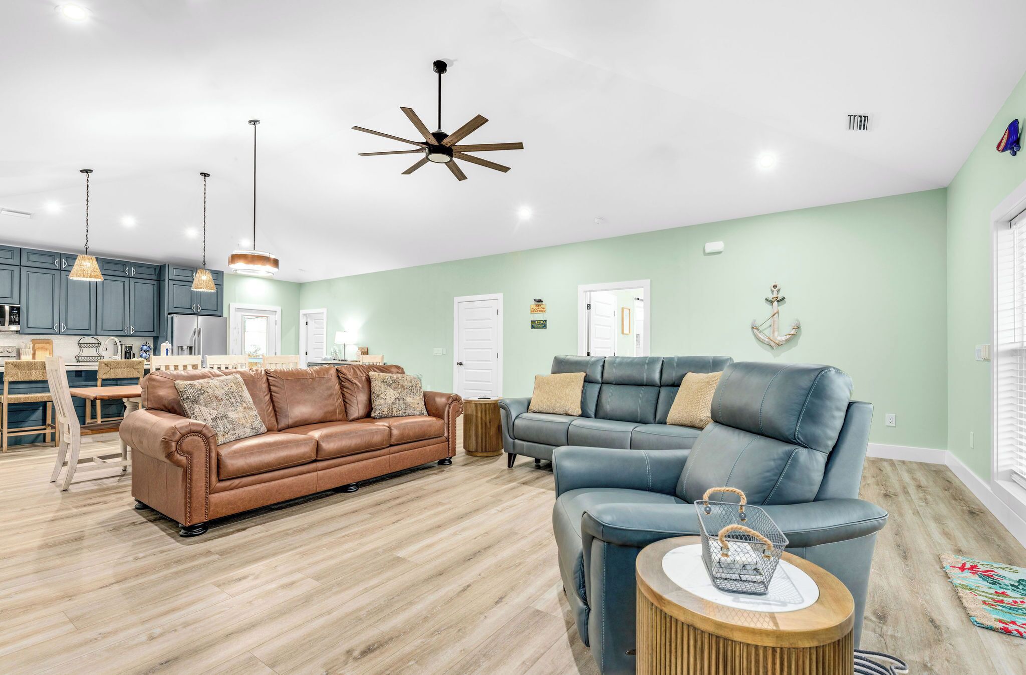 A spacious living area with a brown leather sofa, a blue leather sofa, and a wooden coffee table.