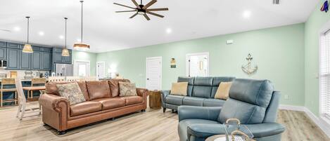 A spacious living area with a brown leather sofa, a blue leather sofa, and a wooden coffee table.