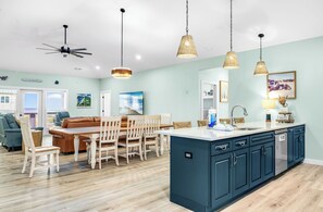 A spacious living area with a dining table, sofa, and kitchen island. - Shrimper and Grits, New Construction, Private Pool, Short Walk to Beach, Beach Gear Credit (St. George Island)