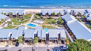 Un hotel sulla costa con diversi edifici, una piscina e vista sulla spiaggia.