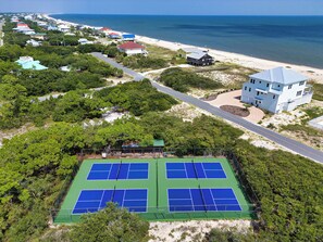 An aerial view of a coastal area with a tennis court, beach, and residential buildings. - Heron's Nest, St. George Plantation, Birding Paradise, Community Pool and Tennis (St. George Island)
