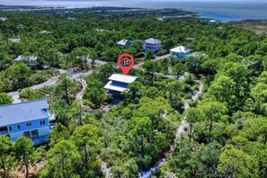 A residential area with multiple houses surrounded by dense greenery and a body of water in the background. - Heron's Nest, St. George Plantation, Birding Paradise, Community Pool and Tennis (St. George Island)