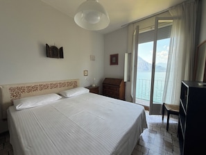 Ein Hotelzimmer mit Bett, Schreibtisch, Stuhl, Fernseher, Lampe und Blick auf ein Gewässer.