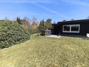 Ein modernes Haus mit einem gepflegten Rasen, einem großen Fenster und einem kleinen Terrassenheizer.