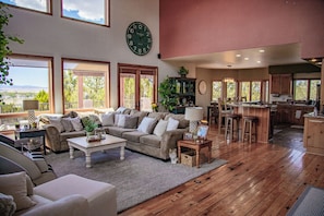 A spacious living area with a large window, a cozy seating arrangement, and a kitchen area.