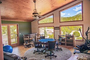 A room with a pool table, exercise equipment, and large windows offering a view of the outdoors.
