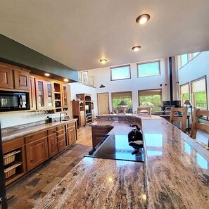 A spacious kitchen with granite countertops, wooden cabinets, and a central island.