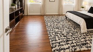 A bedroom with a bed, a wooden floor, a bookshelf, and a window with curtains. - 4 BD, Pet Friendly - Modern chic beautiful, fenced yard (Vancouver)