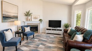 A modern living room with a fireplace, a large TV, and a geometric patterned rug. - 4 BD, Pet Friendly - Modern chic beautiful, fenced yard (Vancouver)
