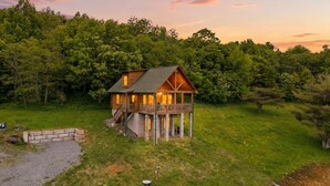 Eine Holzhütte mit Balkon, umgeben von üppiger Vegetation und Bäumen.