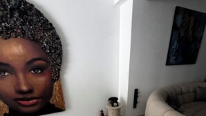 A modern living room with a large wall mural, a round seating area, and a fire extinguisher. - 8-enclosure room - BS HOUSE HÔTEL (Pointe-à-Pitre)