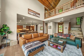 Ein geräumiger Wohnbereich mit hoher Decke, ein Essbereich und eine Treppe, die in ein Obergeschoss führt.
