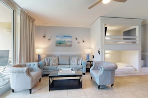 A living room with a sofa, armchairs, a coffee table, a bunk bed, and a painting on the wall. - Life’s A Beach Condo - Waterscape B230 (Fort Walton Beach)