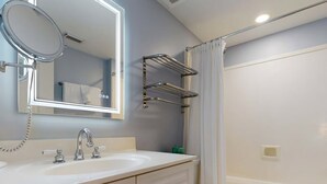 Un bagno con lavandino, specchio, WC e tenda della doccia.