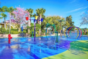 Ein Wasserpark mit bunten Spielgeräten, einem roten Hydranten und Palmen.