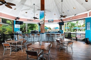 Ein Restaurant mit Terrassensitzgelegenheiten, Deckenventilatoren und Blick auf den Strand.