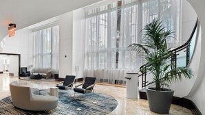 A spacious lobby with a marble floor, large windows, and modern seating. - Sorrento 1514 (Miami Beach)