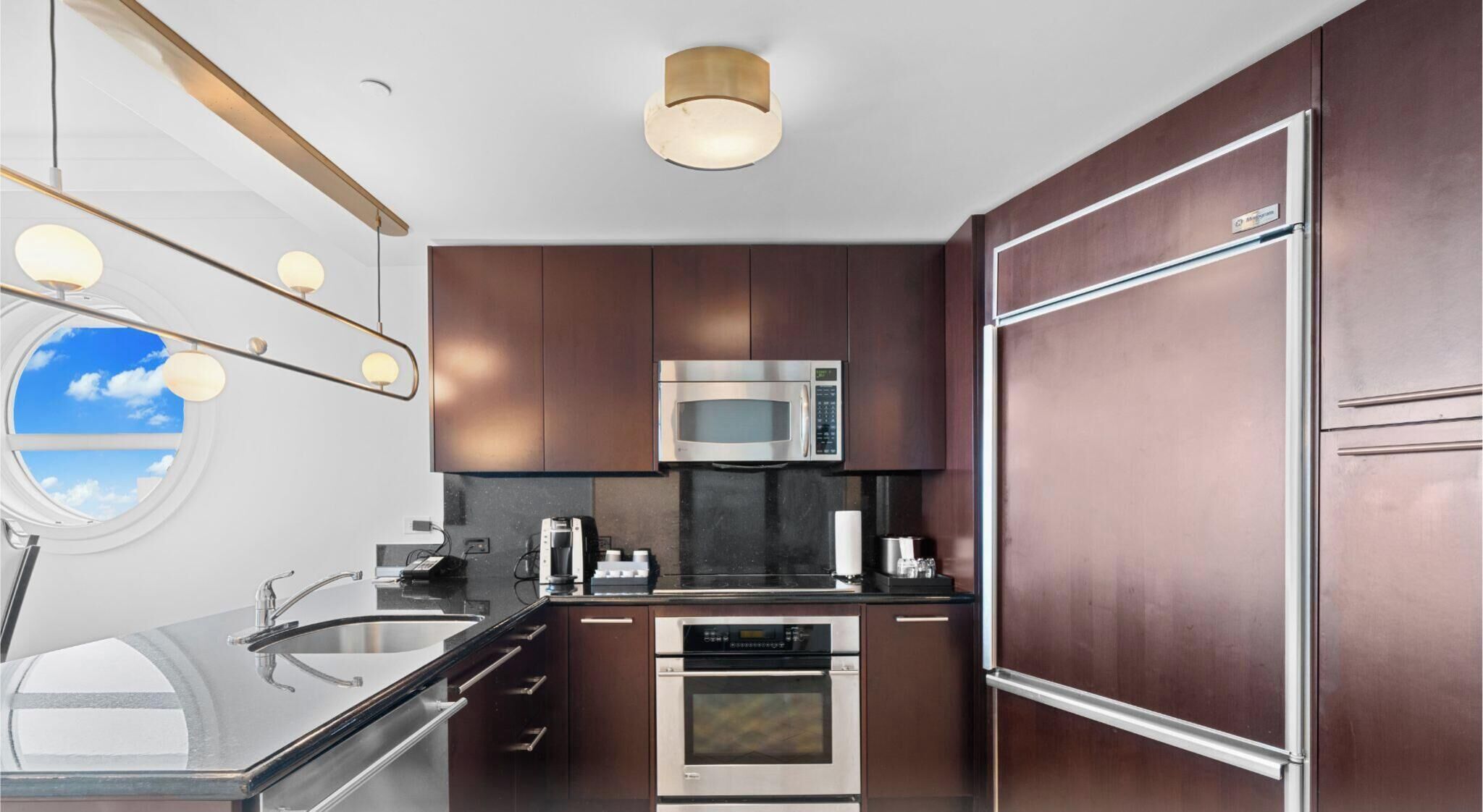 A modern kitchen with stainless steel appliances, wooden cabinets, and a built-in oven.