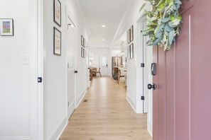Un couloir aux murs blancs, orné de tableaux encadrés, et doté d’un plancher en bois.