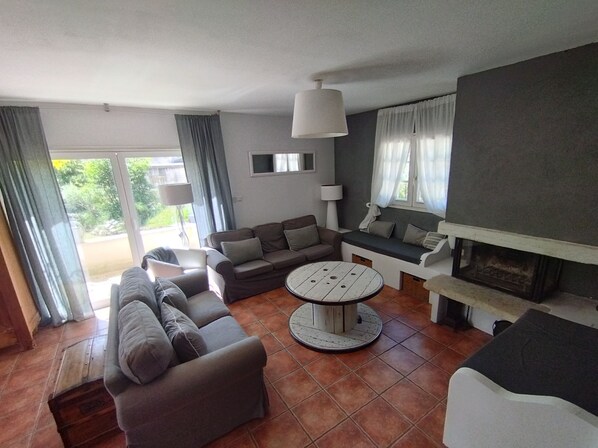 A living room with a sofa set, a round coffee table, and a fireplace. - Country house facing the Ventoux (Modène)