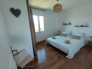 A bedroom with a bed, bedside tables, a hanging light fixture, a window, and a wall-mounted shelf. - Country house facing the Ventoux (Modène)