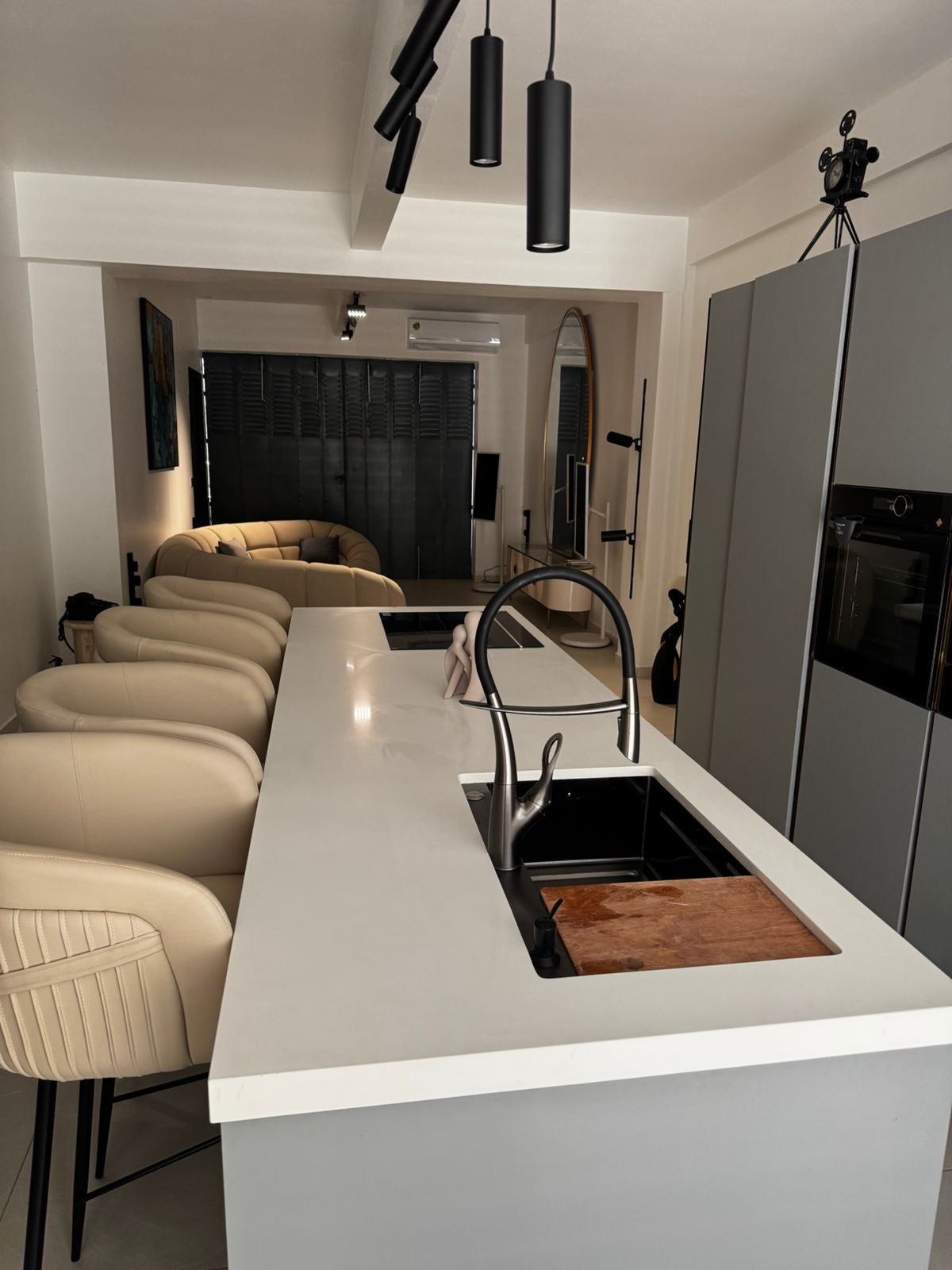 A modern kitchen with a white countertop, a stainless steel sink, and a built-in oven.