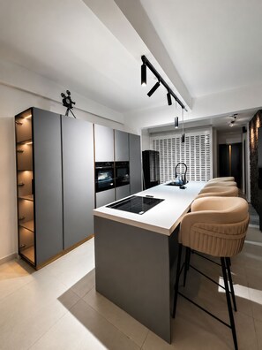 Een moderne keuken met een centraal eiland, barkrukken en inbouwapparatuur.