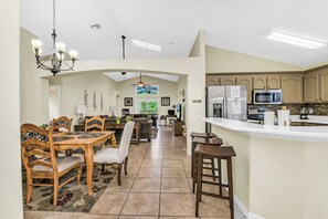 A spacious kitchen with a large island, a dining area with wooden furniture, and a living room with a sofa and coffee table. - Disney World Retreat Oasis, Pool, Privacy & Comfort. (Kissimmee)