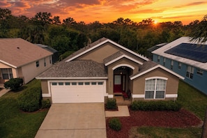 A residential house with a garage, a front porch, and a driveway. - Disney World Retreat Oasis, Pool, Privacy & Comfort. (Kissimmee)