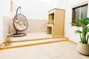 Ein Zimmer mit Hängesessel, Topfpflanze und einem kleinen Tisch mit Dekoration.