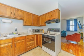 A kitchen with wooden cabinets, a stove, a microwave, and a sink.