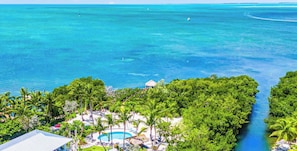 A resort with a pool, palm trees, and a view of the ocean. - Peninsula Villa Heated Pool Sunset Point (Islamorada)