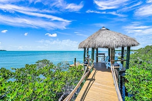 A wooden deck leading to a thatched-roof structure with outdoor seating. - Peninsula Villa Heated Pool Sunset Point (Islamorada)