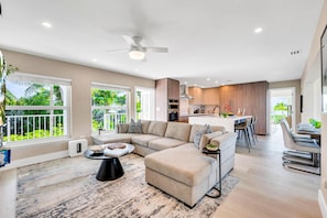 A spacious living area with a large sofa, a coffee table, and a dining area with chairs and a table. - Peninsula Villa Heated Pool Sunset Point (Islamorada)
