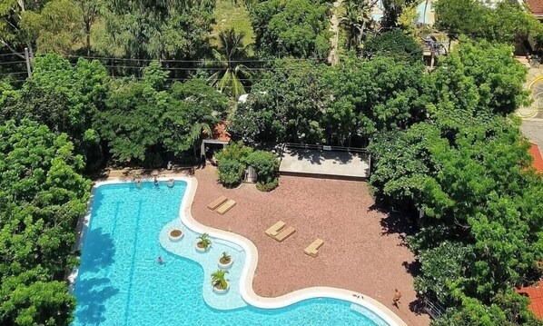 Et resort med en stor swimmingpool, frodigt grønt område og havudsigt.