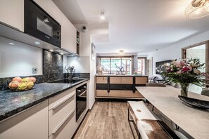 Eine moderne Küche mit Backofen, ein Essbereich mit einer Bank und Blick ins Freie.