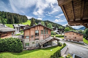 Eine Holzhütte mit Steinunterbau, einem geneigten Dach und Blick auf ein grünes Tal und Berge.