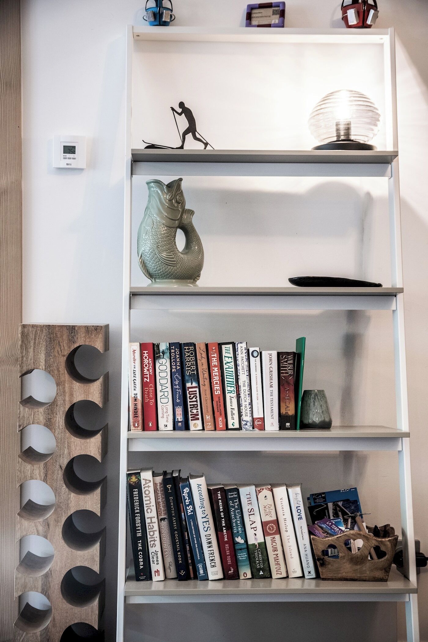 A bookshelf with books, a decorative vase, and a small figurine.