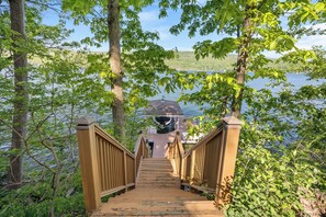 A wooden staircase leading to a gazebo by a lake, surrounded by trees.